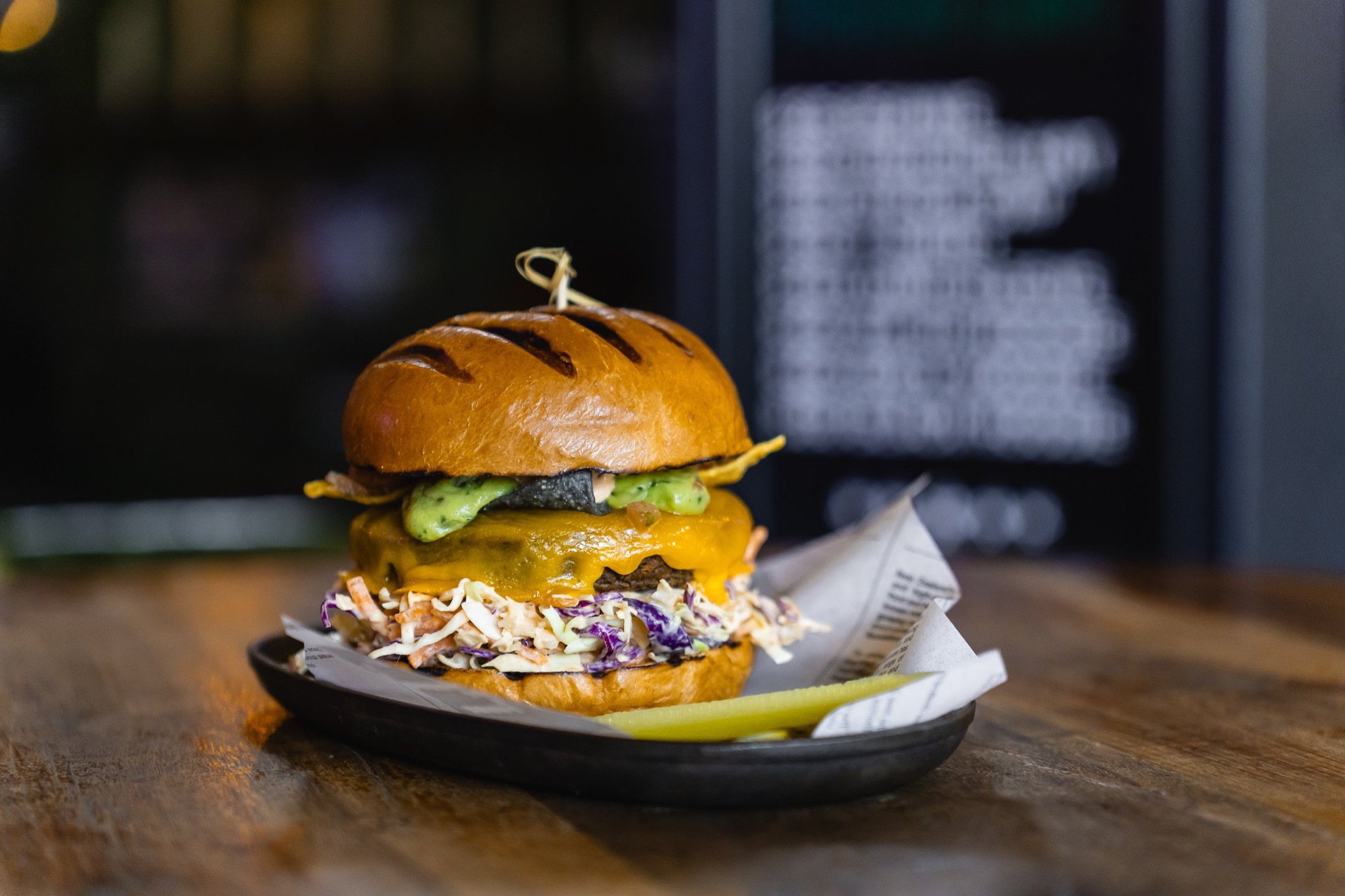 Cheeseburger with coleslaw and pickle on a plate at The Locker Room