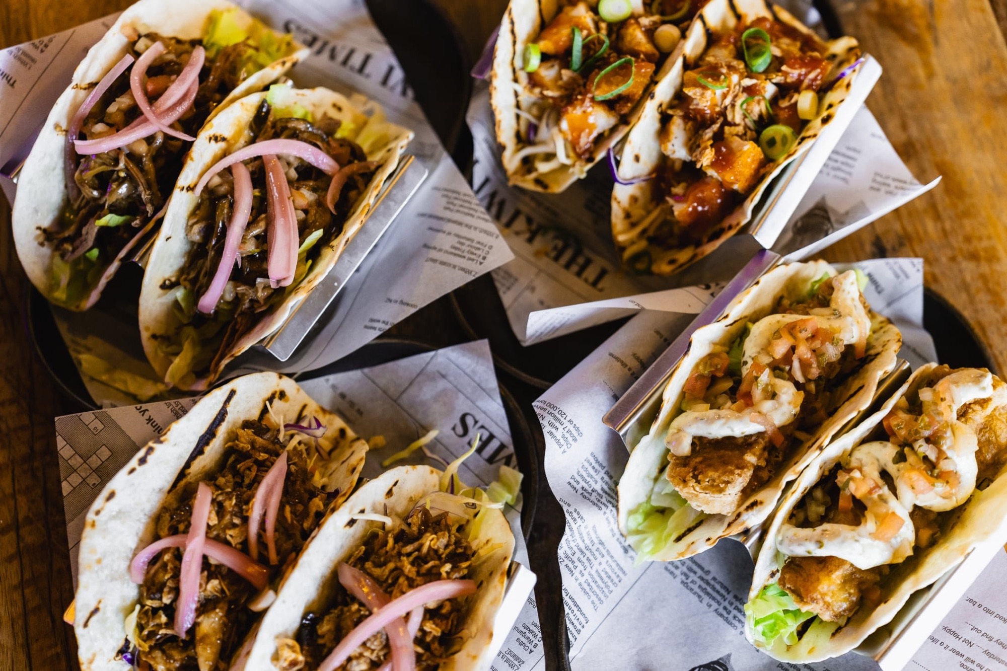 Four loaded taco dishes served on a wooden table at The Locker Room
